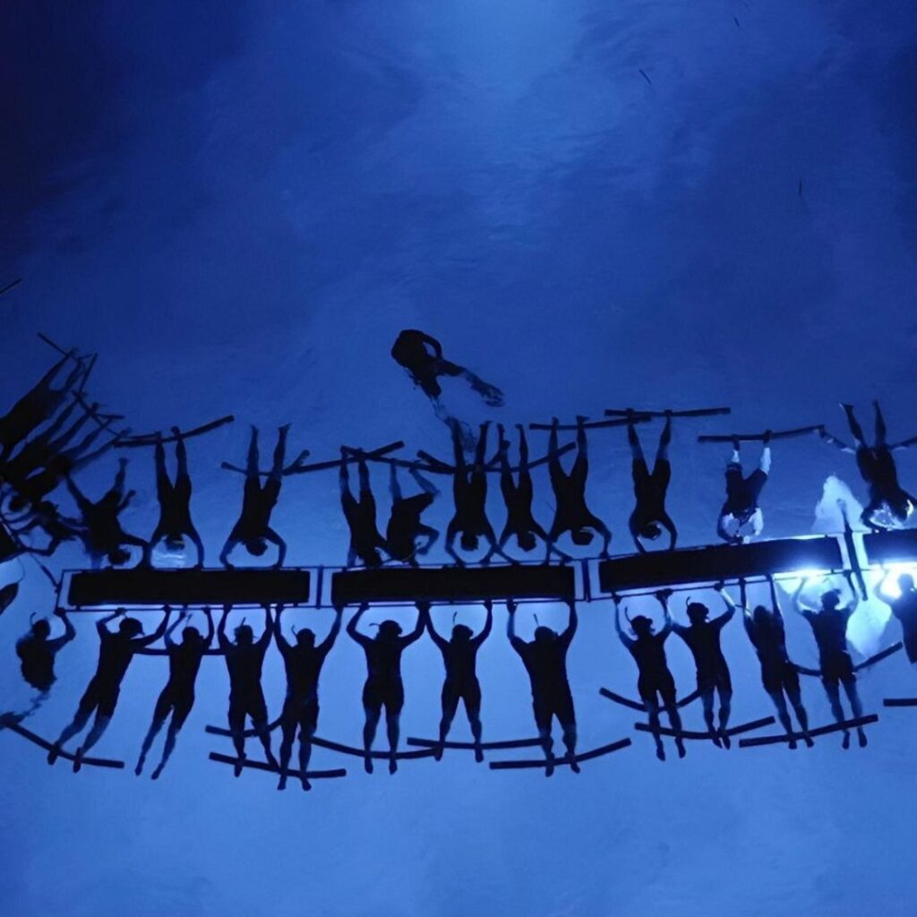 A group of people in the water hanging onto boats looking into the water