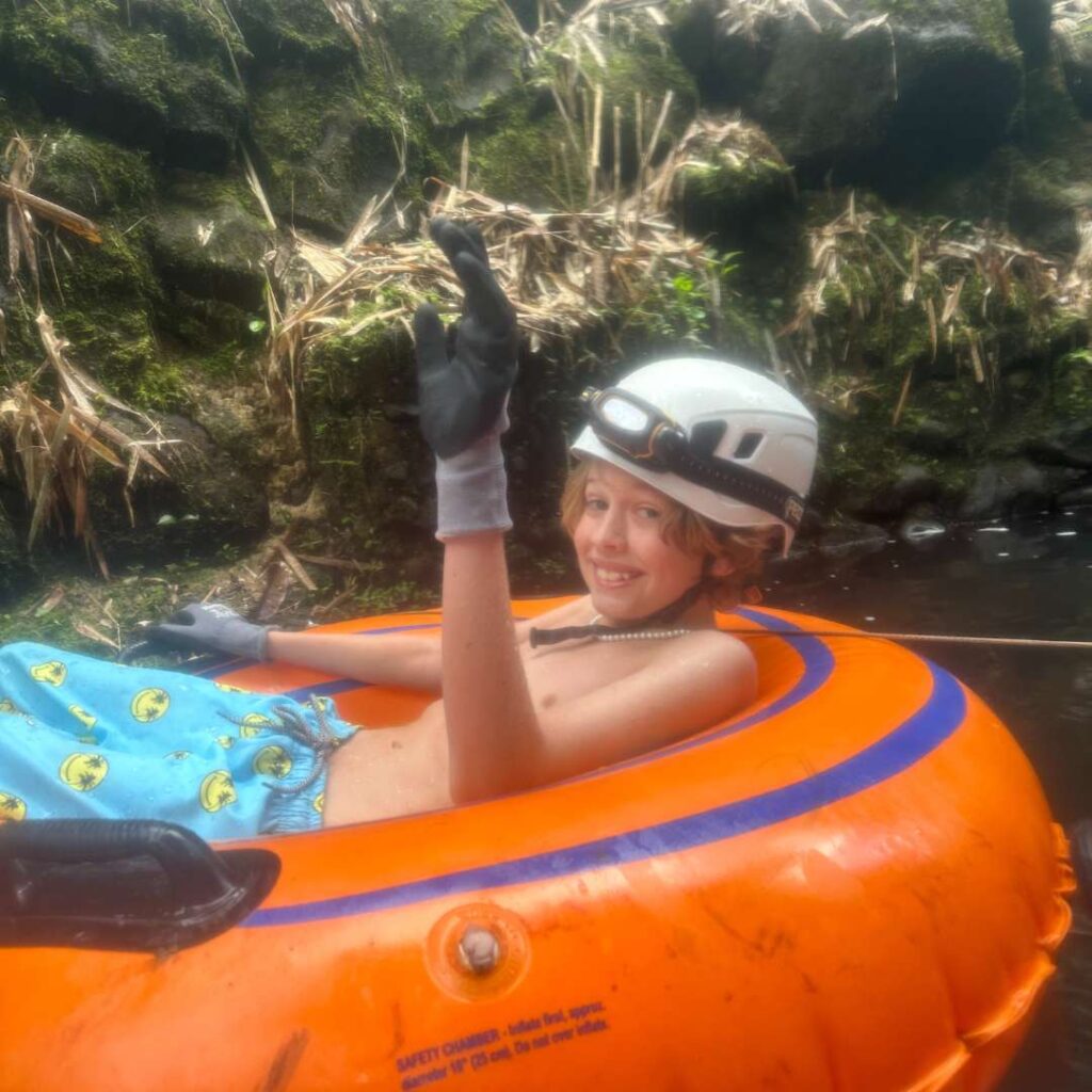 A boy on an orange tube wearing a helmet in water