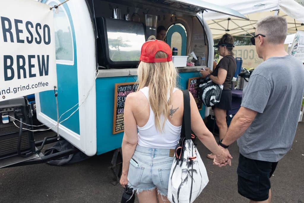A woman and man holding hands looking at a coffee cart menu