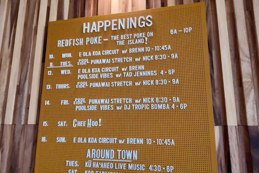 A yellow sign with white letters that shows events happening at Wayfinder Waikiki Hotel