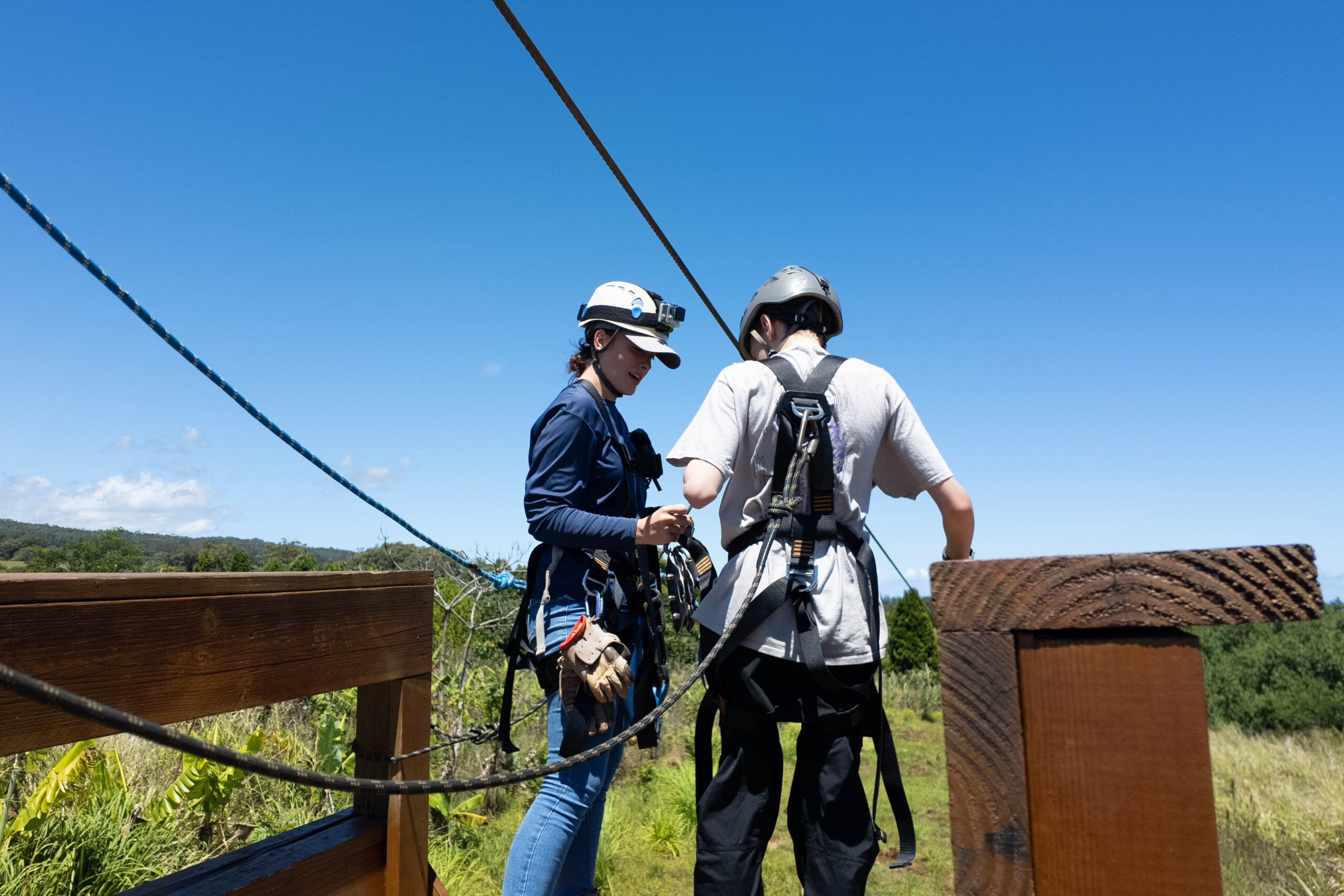A woman helping a boy on a zipline