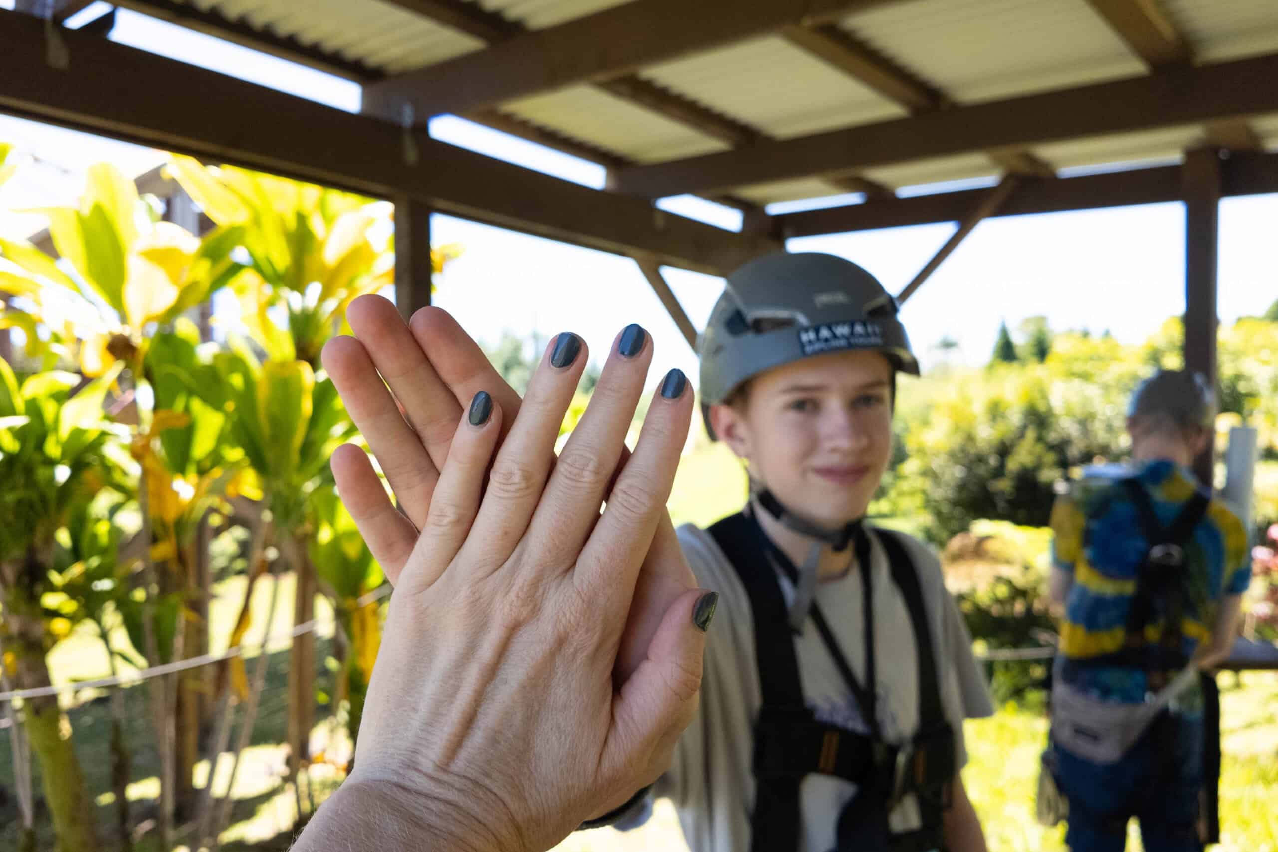 A boy in a helmet giving the person taking the picture a high five