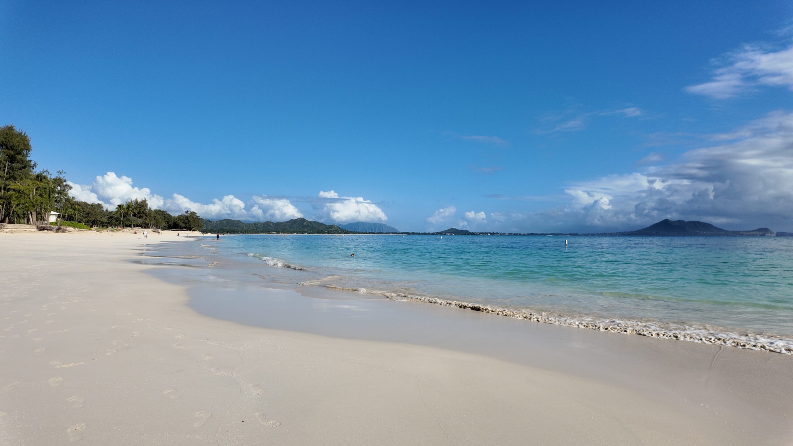 Kailua beach with calm water, palm trees and mountains in the distance.