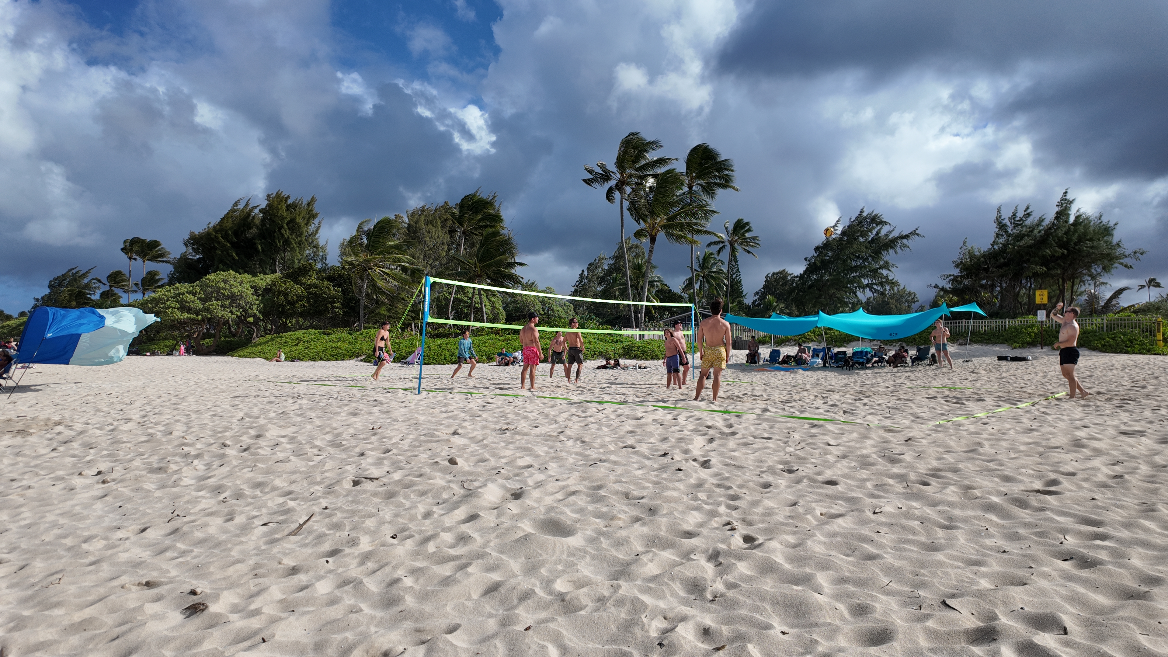 A group of people playing beach volleyball on a sunny day