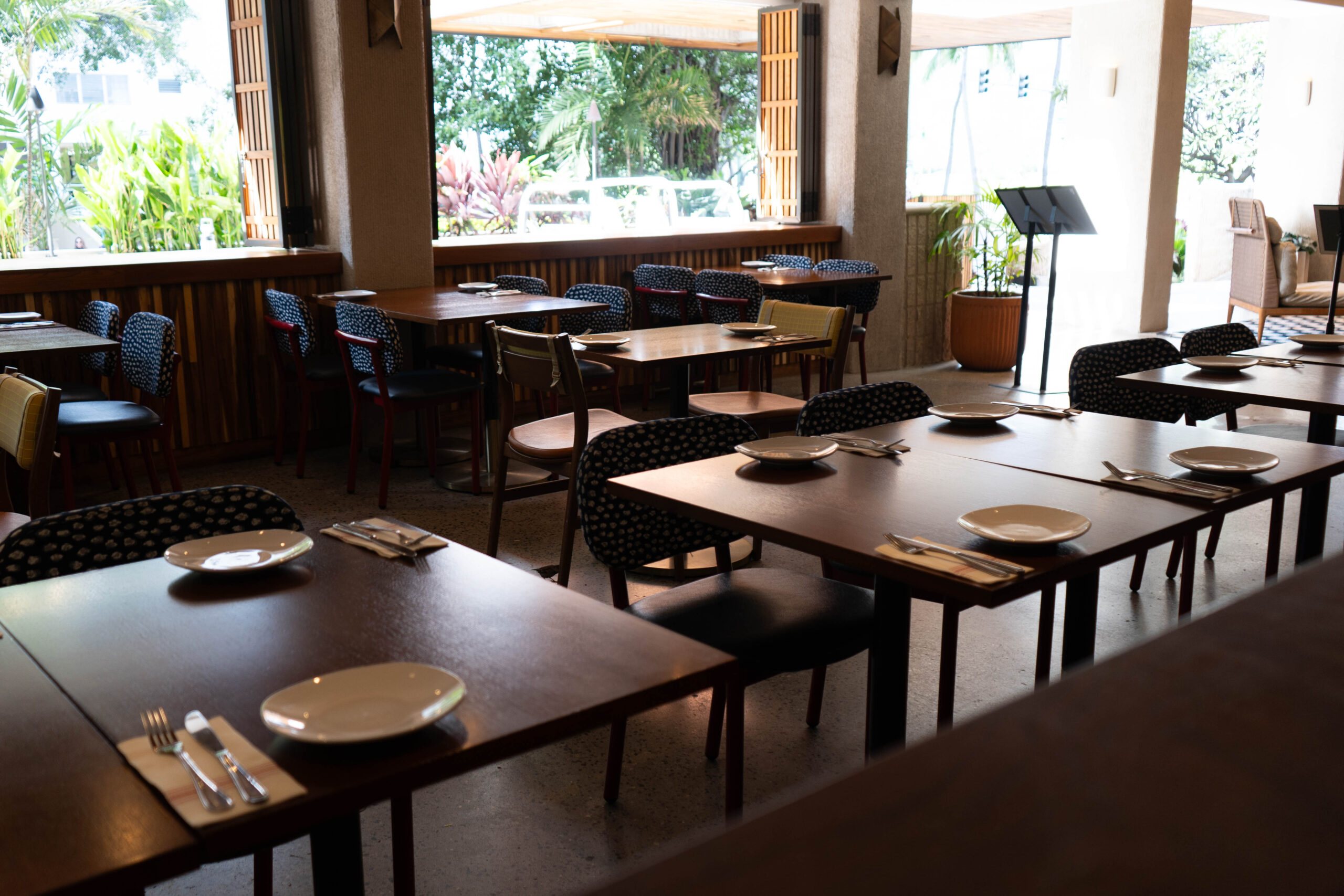 A restaurant with wooden tables and open windows