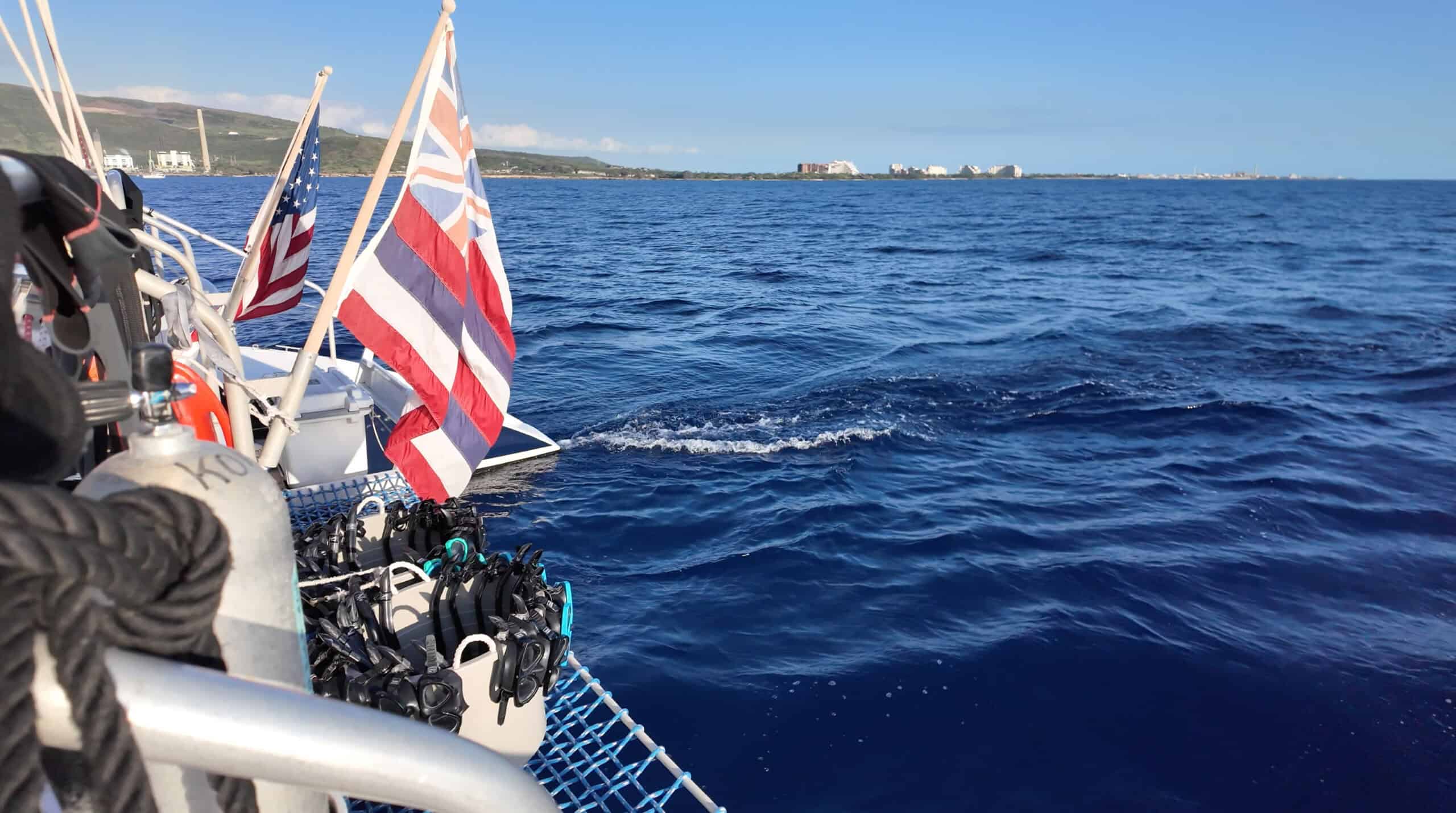 The end of a boat with British and American flags and snorkel fins and masks.