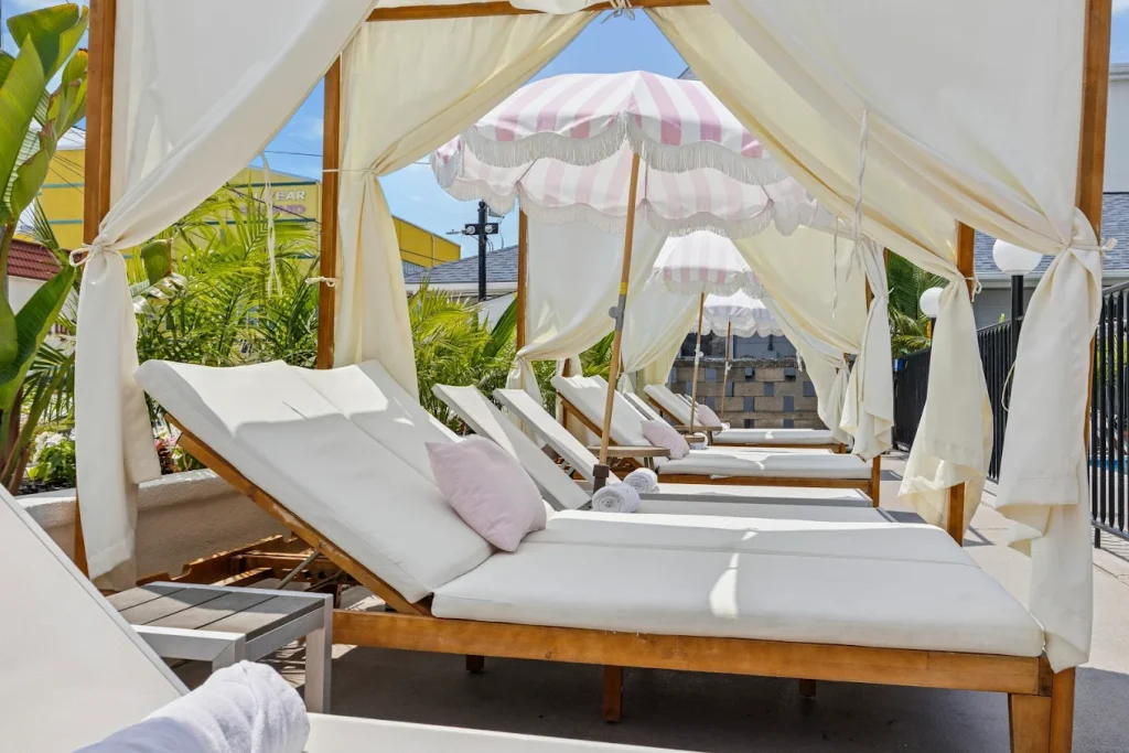 White cabanas and pool chairs with pink and white pillows